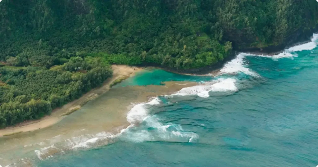 Aerial view of a Hawaiian island coastline with turquoise water and lush green mountains