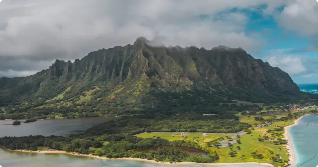 Aerial view of a Hawaiian island coastline with turquoise water and green mountains, ideal for a honeymoon