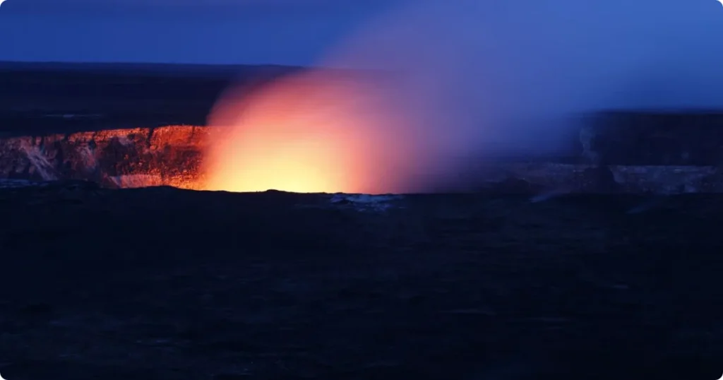 Kilauea crater in Hawaii Volcanoes National Park with volcanic steam and glowing lava visible from the rim