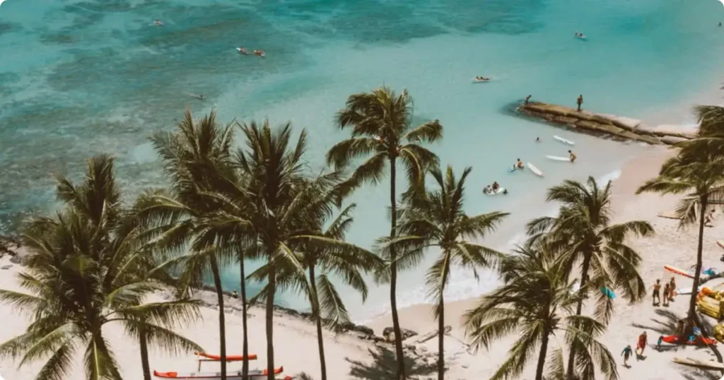 Aerial view of a turquoise Hawaiian beach coastline representing the Maui vs Oahu comparison for first-time visitors